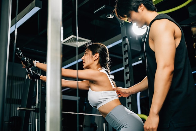 Männlicher Fitnesstrainer, der einer Frau beibringt, wie man eine Pulldown-Kabelmaschine benutzt