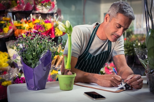 Männlicher Florist, der auf Zwischenablage schreibt