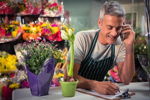 Männlicher Florist, der Bestellung auf Handy annimmt