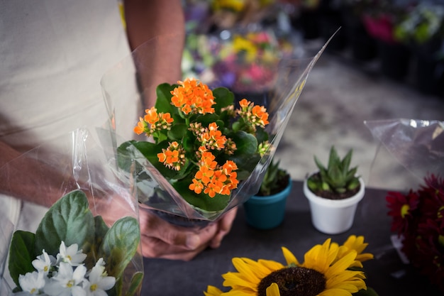 Männlicher Florist, der Blumenstrauß am Blumenladen hält