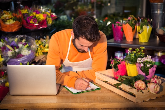 Männlicher Florist, der Reihenfolge im Notizblock notiert