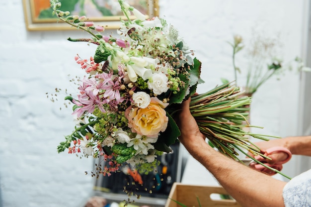 Männlicher Florist, der schönen Blumenstrauß beendet