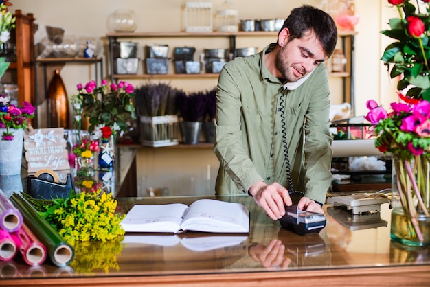 Männlicher Florist, der telefonisch Bestellungen in einem Blumenladen entgegennimmt