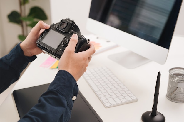 Männlicher Fotograf, der an seinem Schreibtisch sitzt und in die Kamera schaut