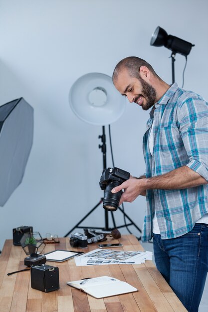 Männlicher Fotograf, der aufgenommene Fotos in seiner Digitalkamera überprüft