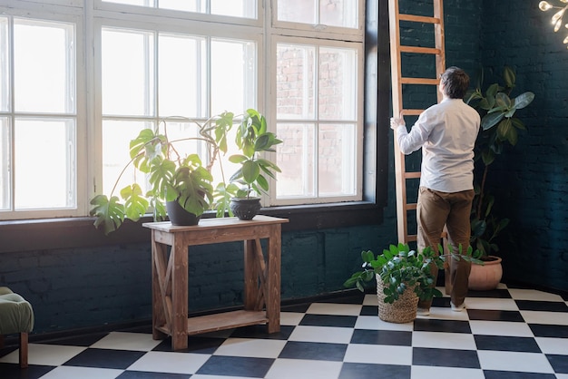 Männlicher Fotograf, der im stilvollen blauen Wohnzimmer mit Pflanzen arbeitet