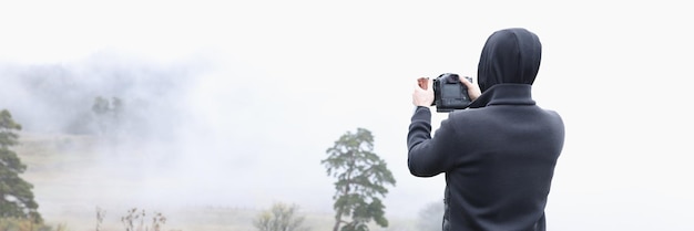 Männlicher Fotograf fotografiert neblige Herbstlandschaft mit schlammigen Straßen, Tourismusreisen und