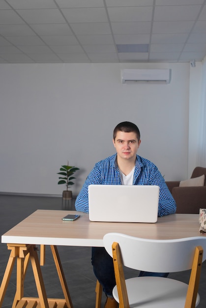 Männlicher Freiberufler arbeitet zu Hause mit einem Laptop. Fernarbeitskonzept