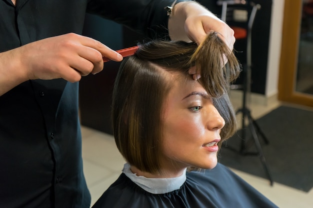 Männlicher Friseur bereitet sich auf den Haarschnitt der schönen Frau im Schönheitssalon vor.