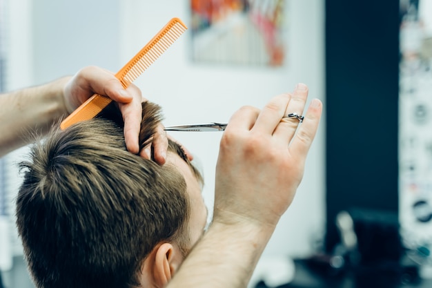 Männlicher Friseur, der Haare eines Kunden schneidet