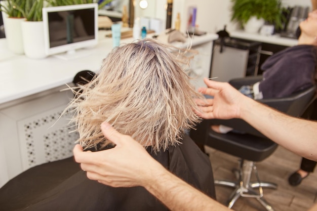 Männlicher Friseur, der junge Frau im Schönheitssalon bedient