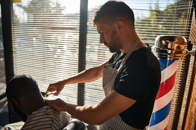 Männlicher Friseur macht Haarschnitt mit Vintage-Haarschneider