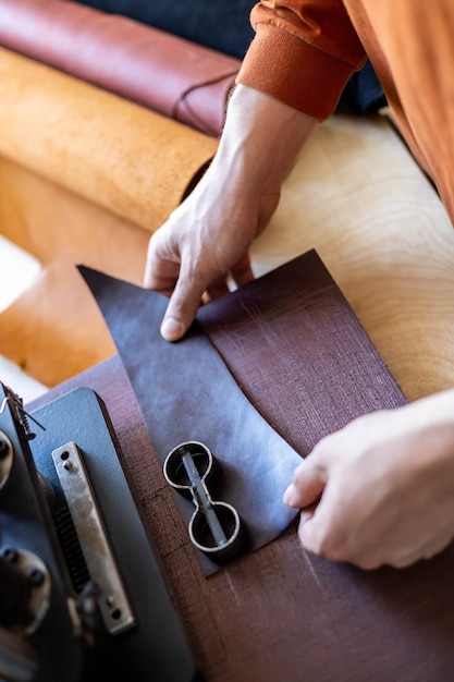 Männlicher Gerber, der mit Handpressgerät-Maschinen-Schnittmuster auf Material-Lederwerkstatt arbeitet