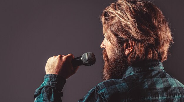 Männlicher Gesang mit Mikrofonen. Mann mit Bart, der ein Mikrofon hält und singt. Bärtiger Mann in Karaoke singt ein Lied in ein Mikrofon.