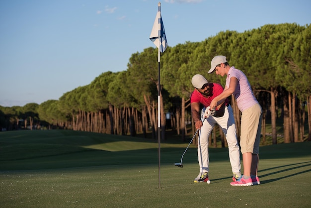 männlicher golflehrer, der weibliche golfspieler unterrichtet, persönlicher trainer, der unterricht auf dem golfplatz gibt