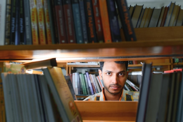 Männlicher indischer student in der bibliothek mit buch