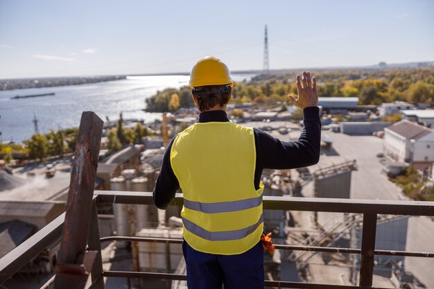 Männlicher Ingenieur, der draußen in der Fabrik hallo-Geste macht