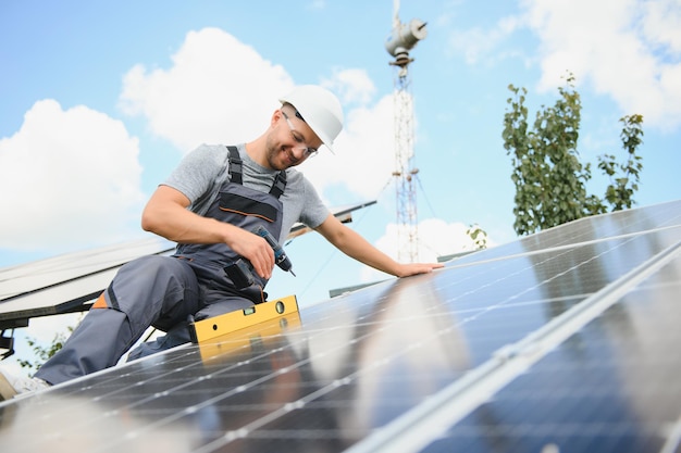 Männlicher Ingenieur im Schutzhelm, der ein Solar-Photovoltaik-System installiert Ökologisches Konzept für alternative Energie