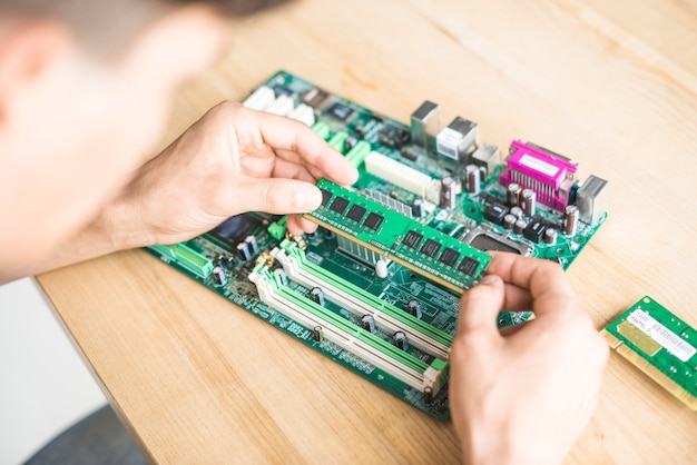 Männlicher IT-Techniker, der RAM-Speichermodul im Motherboard hält