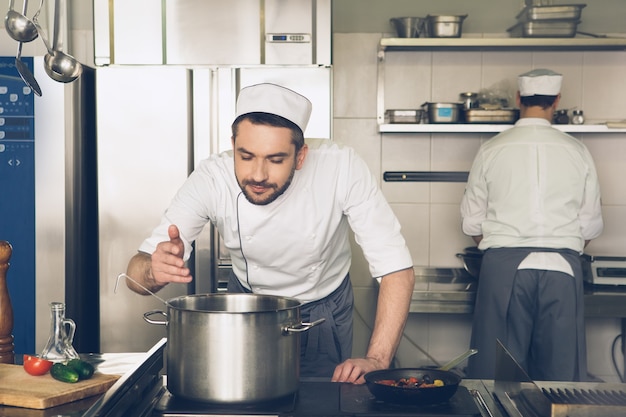 Männlicher japanischer Restaurantkoch, der in der Küche kocht, riecht das Gericht?