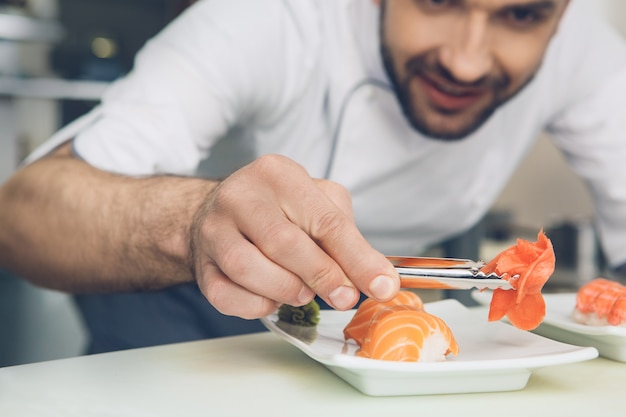 Männlicher japanischer Restaurantkoch, der in der Küche kocht und Zutaten hinzufügt