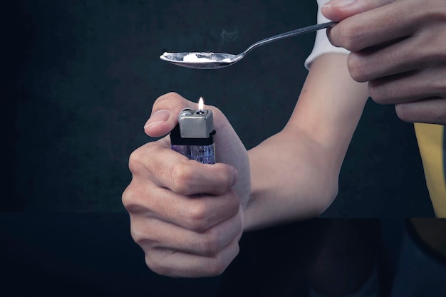 Männlicher Junkie kocht Heroin mit einem Feuerzeug