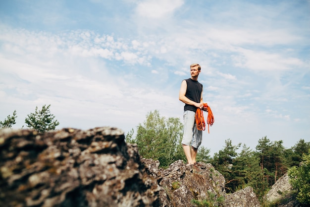 Foto männlicher kletterer, der auf dem felsen mit einem seil steht