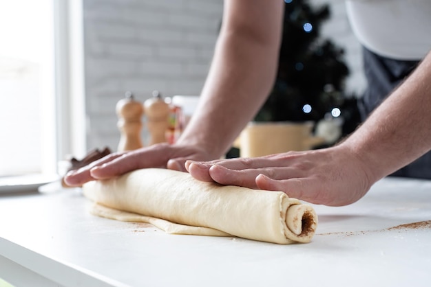 Männlicher Koch, der mit Teig arbeitet und Zimtbrötchen kocht