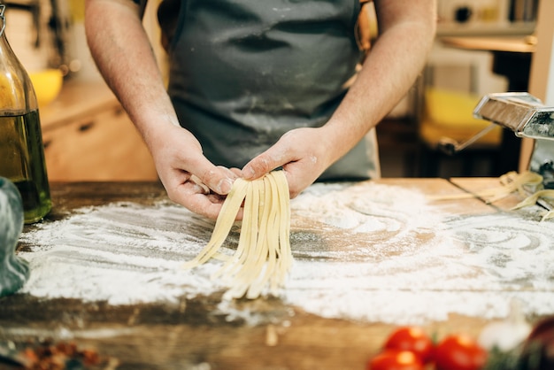 Männlicher Koch, der Teig kocht und Nudelmaschine vorbereitet