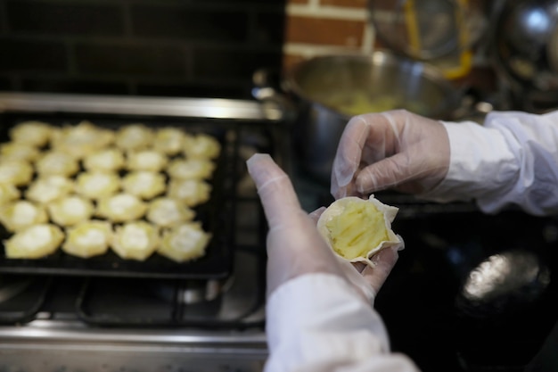 Männlicher Koch verwendet Zutaten für die Zubereitung von Mehlprodukten auf dem Küchentisch