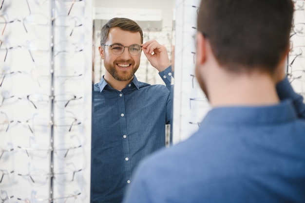 Männlicher Kunde, der im Optikgeschäft ein neues Brillengestell für seine neue Brille auswählt