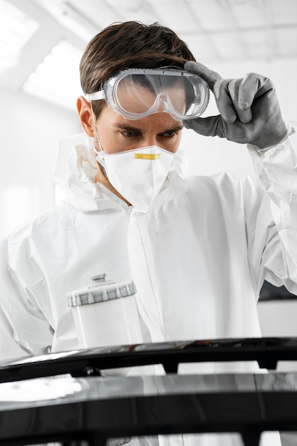 Foto männlicher maler im hazmat-anzug im autohaus