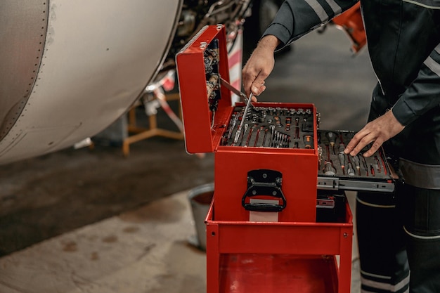 Männlicher Mechaniker mit Instrumentenkasten im Hangar