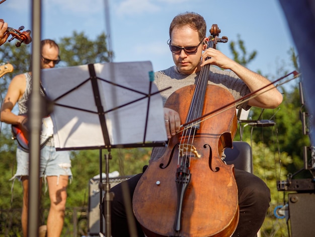 Männlicher Musiker, der im Freien Violoncello im Orchester spielt