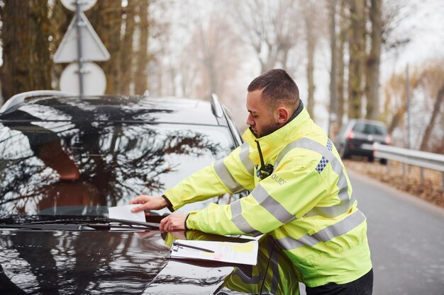 Männlicher Polizist in grüner Uniform, der das Fahrzeug mit einer feinen Liste belegt.