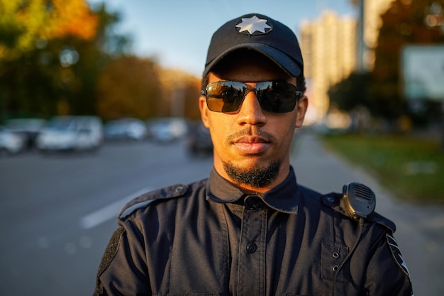 Männlicher Polizist in Uniform und Sonnenbrille im Freien. Polizisten schützen das Gesetz. Polizist arbeitet an Stadtstraßen-, Ordnungs- und Justizkontrolle