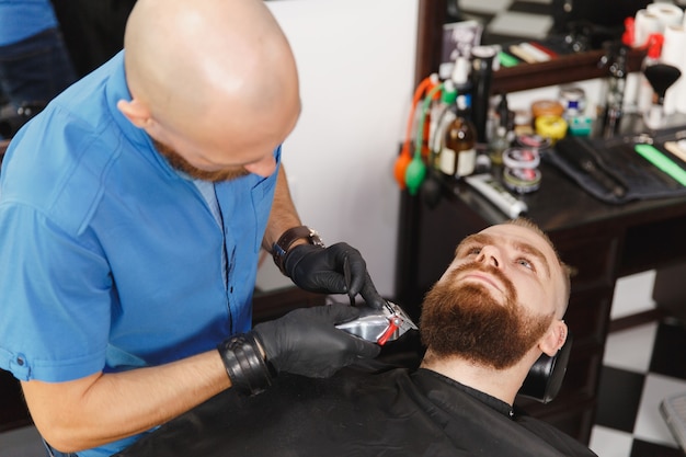 Männlicher professioneller Friseur, der Kunden mit Schermaschine bedient