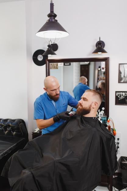 Männlicher professioneller Friseur, der Kunden mit Schermaschine bedient