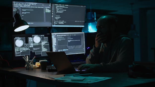 Männlicher Programmierer gähnt und arbeitet an einer neuen Schnittstelle und fühlt sich spät in der Nacht schläfrig. Müde Softwareingenieure, die Datenbankinformationen eingeben, um ein Sicherheitssystem zu erstellen, sind erschöpft. Handschuss.