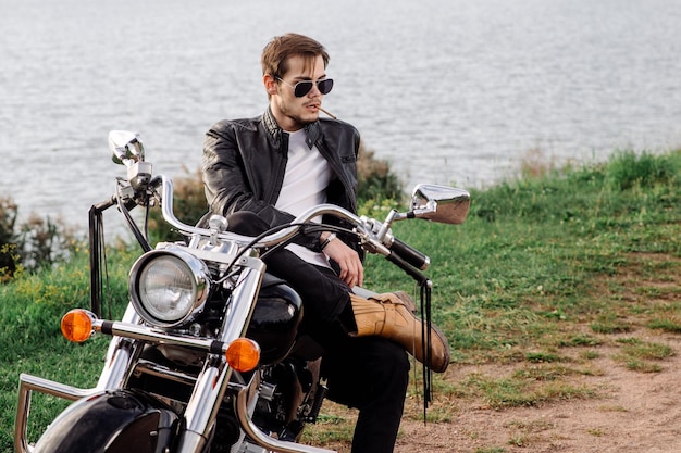 Männlicher Radfahrer, der auf dem Motorrad sitzt und Zigarette raucht