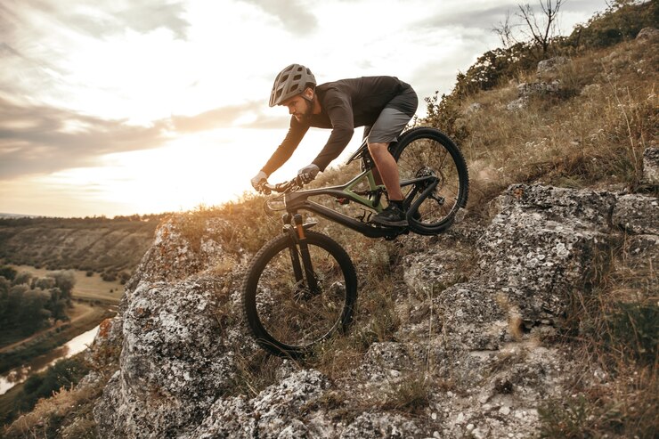 männlicher Radfahrer, der bergab Mountainbike auf felsigem Hang reitet