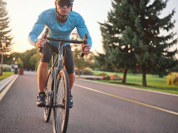 Männlicher Radfahrer mit Sportschutzhelm und Brille, der beim Fahrradfahren fokussiert aussieht