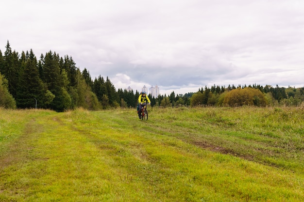 Männlicher Radtourist auf einem Feldweg durch ein Feld an einem bewölkten Herbsttag