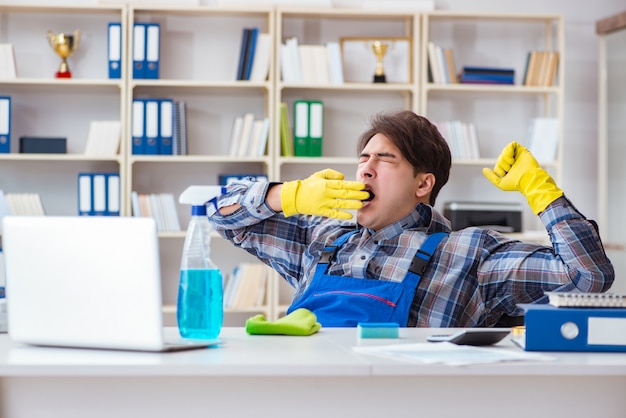 Männlicher Reiniger, der im Büro arbeitet