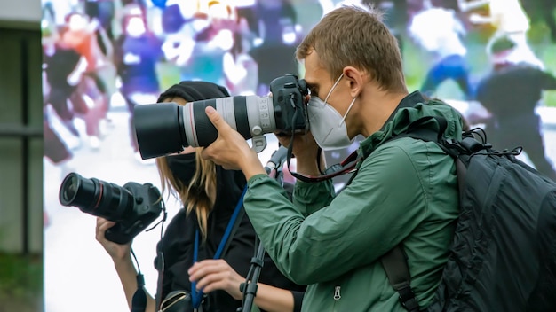 Männlicher Reporter mit einer Kamera Die Arbeit eines Fotografen Aufnahmematerial für Nachrichten