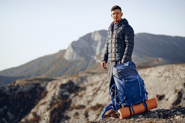 Männlicher Rucksacktourist in der Wanderausrüstung, die an der Spitze des Berges steht