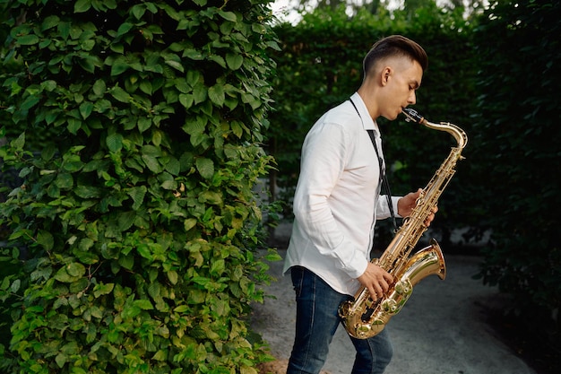 Foto männlicher saxophonist spielt auf der gasse im sommerpark