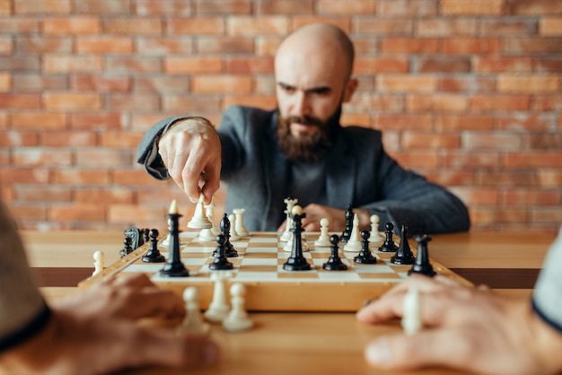 Männlicher Schachspieler mit weißer Figur in der Hand, Königinzug.