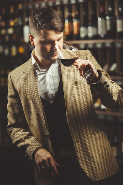 Männlicher Sommelier probiert Rotwein im Keller Professioneller Experte schätzt die Qualität des Getränks