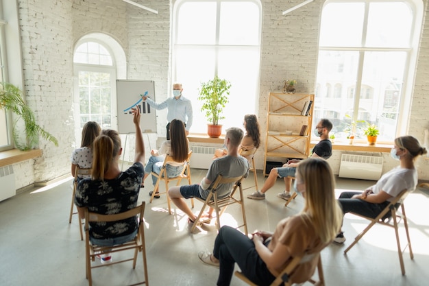 Foto männlicher sprecher, der eine präsentation in der halle des universitätsworkshops oder des konferenzsaals hält